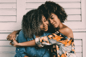 A young lady hugging another lady who is not hugging back